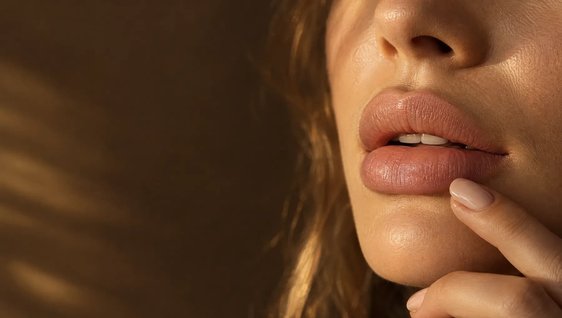 Close up of soft, natural lips with a fingertip resting below